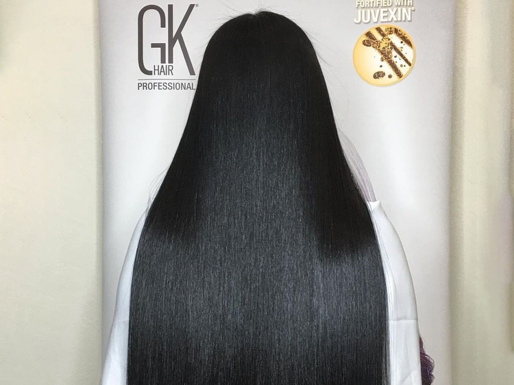 After: long poker-straight glossy black hair from behind against a GK Hair Professional banner reading Fortified with Juvexin