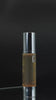 Product film: amber GK Hair Serum 50 ml bottles with silver pump caps on black, oil dripping from a nozzle, Hair Taming System close-up